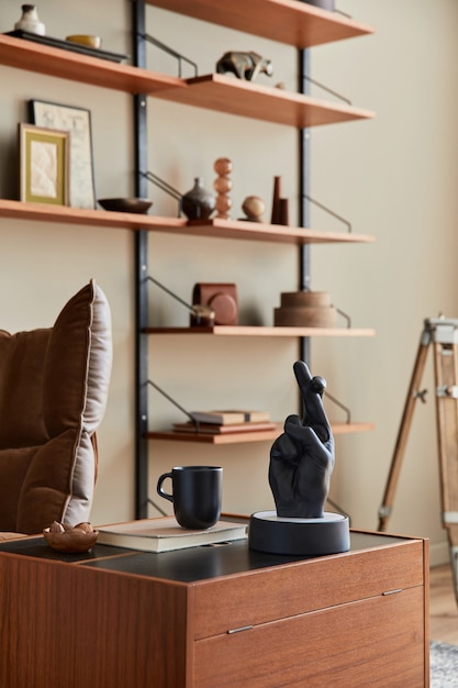 Interior design of living room with brown armchair, coffee table, wooden shelf, book, picture frame, decoration and elegant personal accessories in home decor.