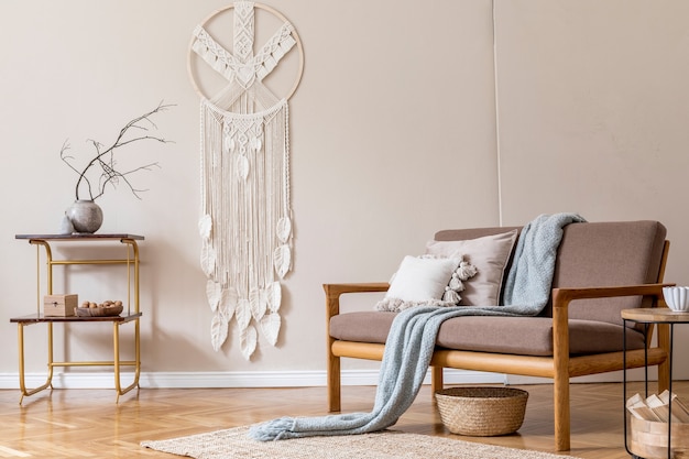 Interior design of living room with stylish brown wooden sofa, macrame, bookstand, lamp, coffee table, plants, decoration and elegant accessories. Beige and japandi concept. .