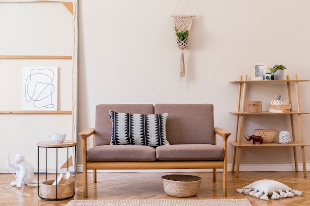 Interior design of living room with stylish brown wooden sofa, macrame, bookstand, lamp, coffee table, plants, decoration and elegant accessories. Beige and japandi concept. .