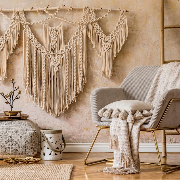 Interior design of oriental living room with modern armchair, macrame, wooden ladder, pillows, decorations and elegant personal accessories in stylish home decor. Wabi sabi wall.