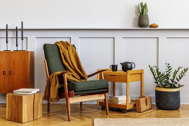 Photo interior design of stylish living room with vintage green armchair, wooden coffeee table, furniture, grey wall, shelf, carpet, plants, decor, book, copy space and elegant personal accessories.