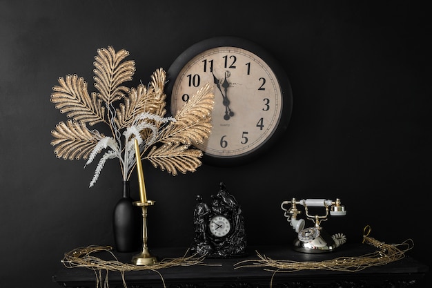 Interior design vases with flowers and candles clock and old retro vintage phone on the fireplace shelf. Vintage interior image in old retro style