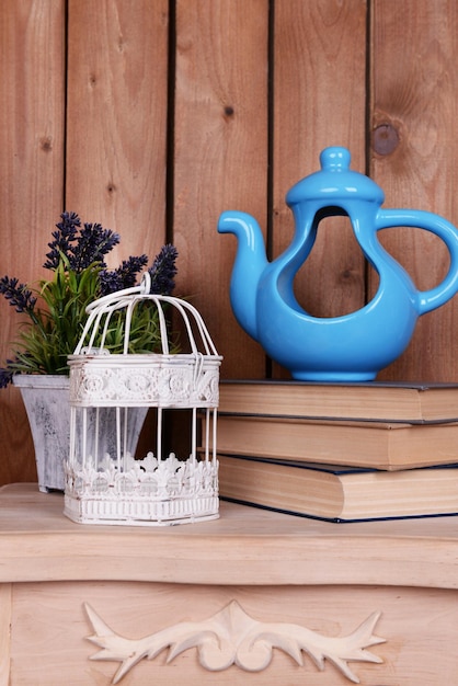 Interior design with decorative pot cage plant and stack of books on tabletop on wooden planks background