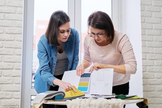 Interior design, designer donne lavoratrici che scelgono campionari di tessuti e accessori per tende