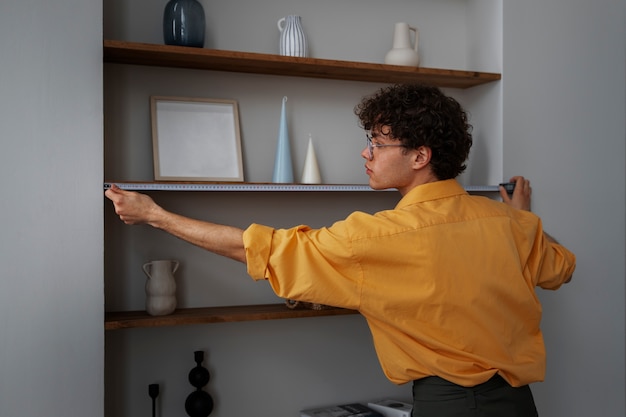 Photo interior designer measuring shelves in home