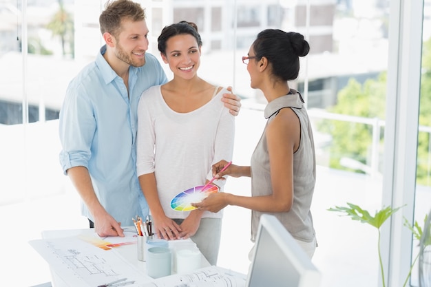 Interior designer showing colour wheel to happy young clients