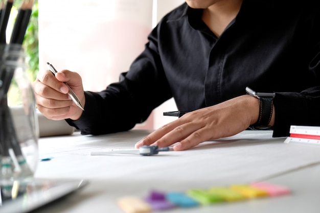 Interior designer working on the blueprints at creative studio workplace.