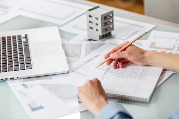 Interior designer working with an apartment plans in a studio with blueprints and laptop on a table