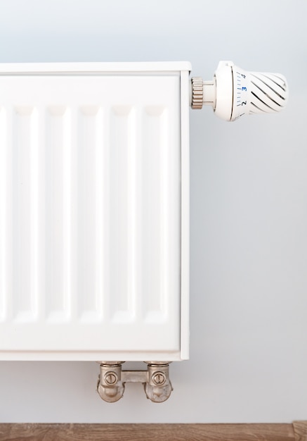 Interior detail. White metal radiator on white wall