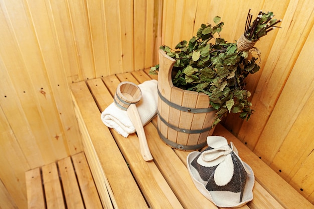 Interior details Finnish sauna steam room with traditional sauna accessories basin birch broom scoop felt hat towel