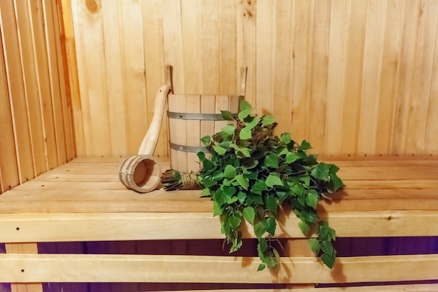 インテリアの詳細伝統的なサウナアクセサリー盆地白樺ほうきスクープを備えたフィンランド式サウナスチームルーム。伝統的な古いロシアの浴場SPAコンセプト。田舎の村風呂のコンセプトをリラックス