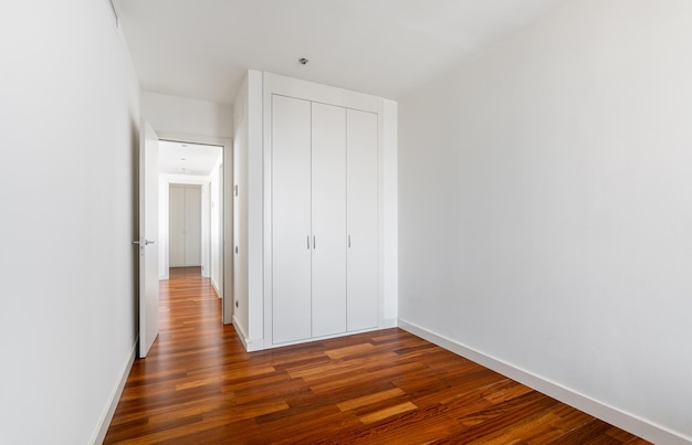 Interior of empty apartment white room with builtin wardrobe parquet floor and view to the hallway