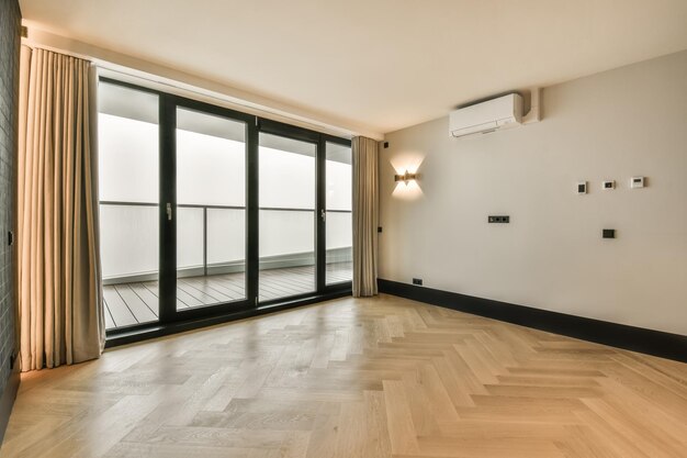 The interior of an empty spacious room with a panoramic window and access to the balcony