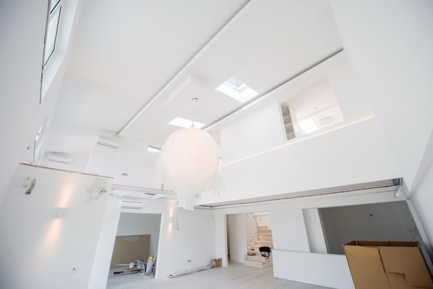 Interior of empty stylish modern open space two level apartment with white walls and large round chandelier in the middle ready to move in