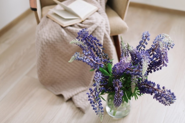 interior home decor with flowers and books bouquet of purple lupins in a vase summer composition