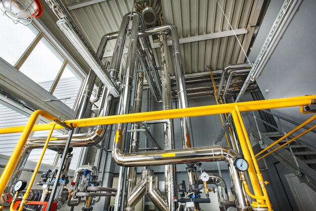 The interior of an industrial boiler house with a multitude of pipes boilers and sensors