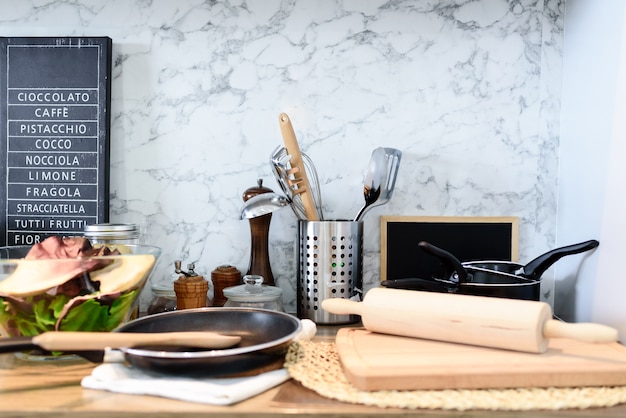 Interior of kitchen room with set of kitchenware on marble