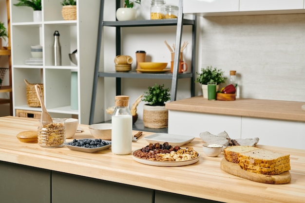 Photo interior of large kitchen with a lot of healthy food and bottle of milk on wooden table