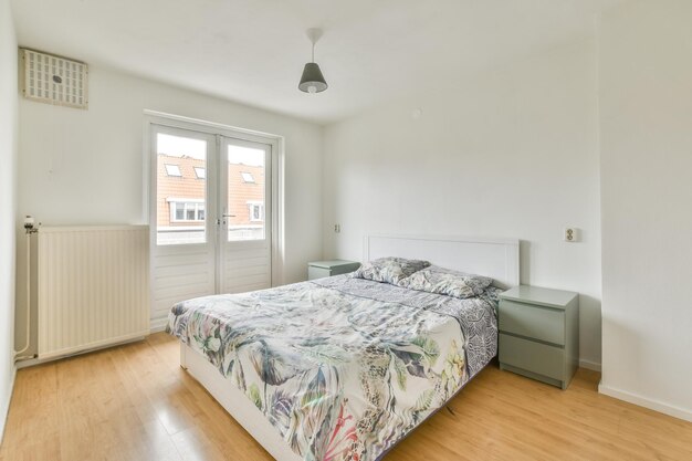 Interior of a light bedroom with white double bed ,grey cupboards and a balcony