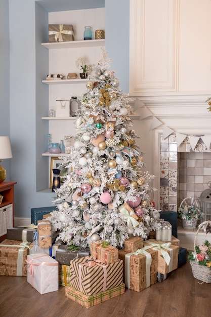 Interior living room with a Christmas tree and decorations.Beautiful holdiay decorated room with Christmas tree with presents under it.New Year's interior with a fir tree in white ,pastel tones