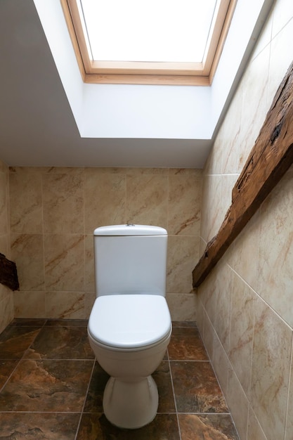 The interior of a modern bathroom with decorative elements made\
of wood a large window over the toilet a low ceiling with a window\
in the restaurant toilet
