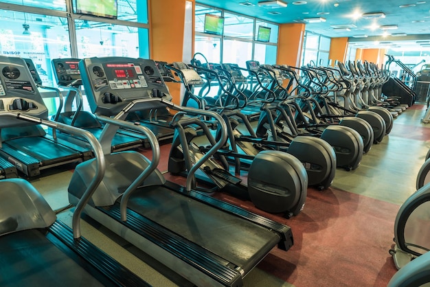Foto interno della moderna sala fitness della palestra con grandi finestre e tapis roulant