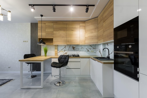 Interior of a modern kitchen, with a bar with wooden inserts and white marble tiles, in a small apartment