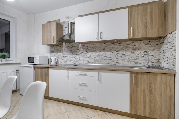 Interior of the modern luxure kitchen in studio apartments in minimalistic style with light white color