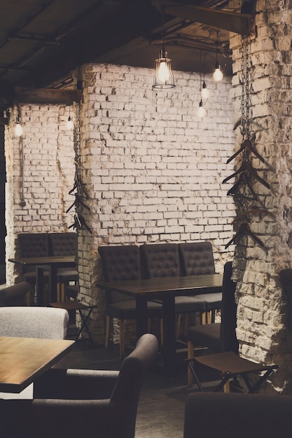 Photo interior of modern restaurant. contemporary design in loft style, big cozy hall with tables and private cabins with brick wall, copy space