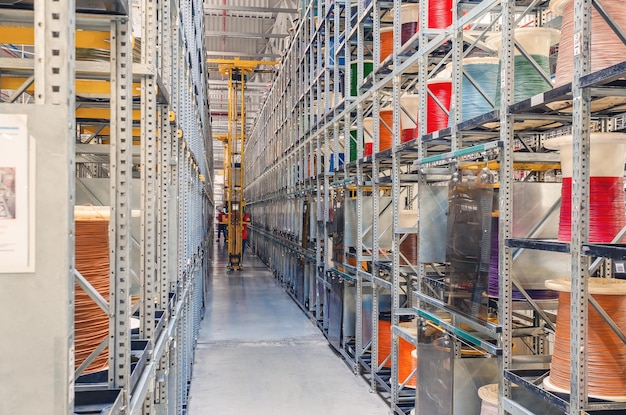 Interior of a modern storage warehouse with coils of colored cable on metal shelves Forklift lift