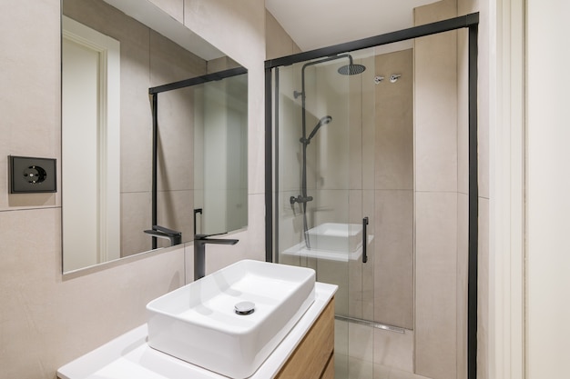 Interior of modern style bathroom in refurbished apartment shower zone sink with black faucet and mi...