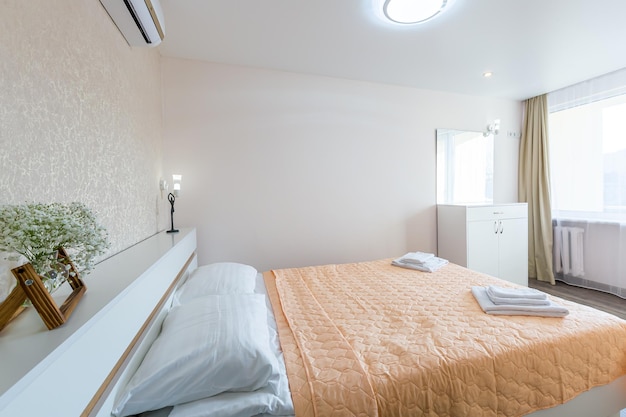 ホテルの白い壁と白い毛布付きの大きなダブルベッドのあるベッドルームのインテリア
