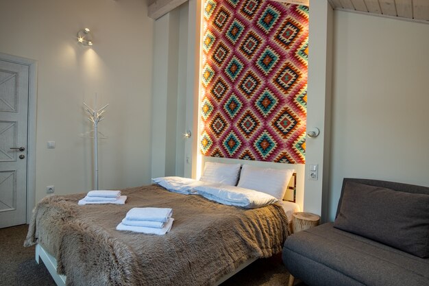 Фото Интерьер просторной спальни гостиницы со свежим бельем на большой двуспальной кровати. уютный современный номер в современном доме.