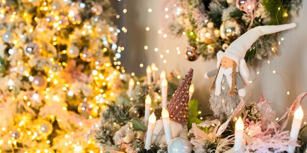 Interior in pink and gold. Christmas tree, wreath are decorated with shiny balls, lights, candles, angel. happy new year.