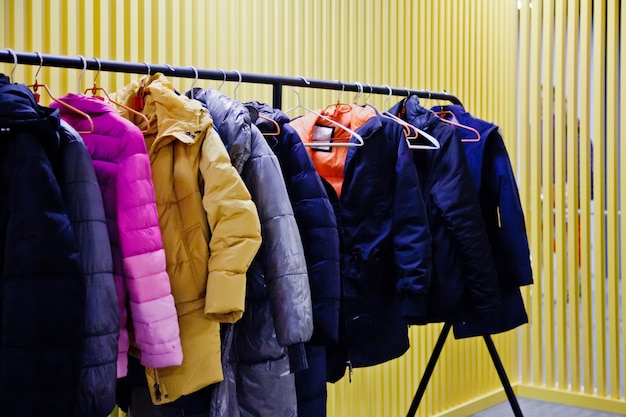 Interior of room storing outdoor clothing for visitors of the\
establishment, with yellow backgrounds. wardrobe, many hangers\
clothes institution, leave outerwear, undress pass into room. copy\
space