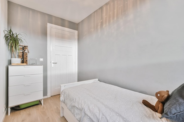 Interior shot of a kid bedroom with a small bed white wardrobe\
and a wooden floor