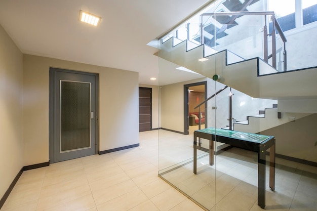 Interior of a singlefamily home staircase with stoneware floors a metal design staircase with tempered glass steps and a structure with glass partitions