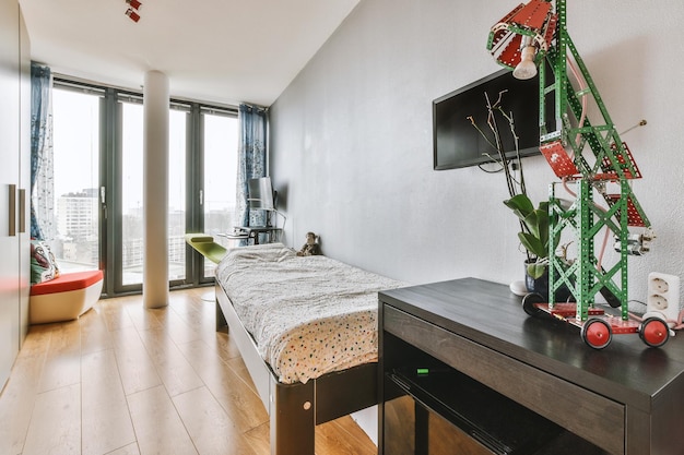 The interior of a small bedroom with panoramic windows and a TV above the bed