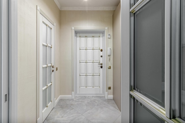 The interior of a stylish house in light colors with white doors with glass