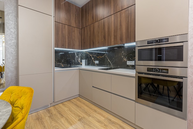 Interior of a stylish modern kitchen in pastel colors, gray, with an insert of black marble