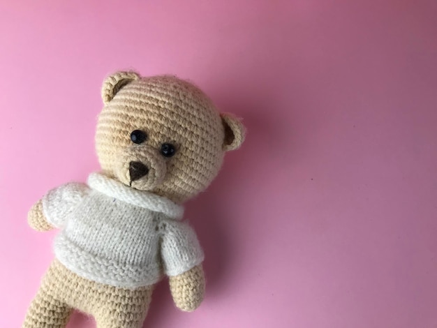 Interior toy soft knitted bear on a pink background in the corner of the background bear made