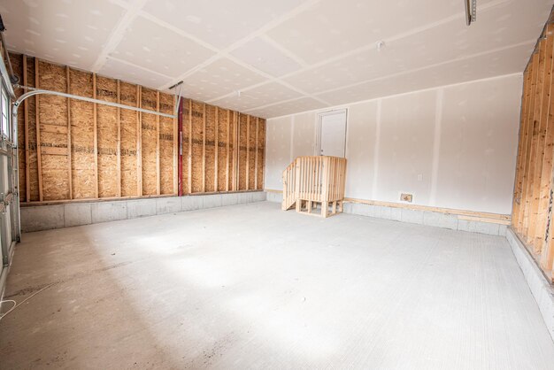 Foto interno di un parcheggio di garage incompiuto con scale di legno per una porta bianca