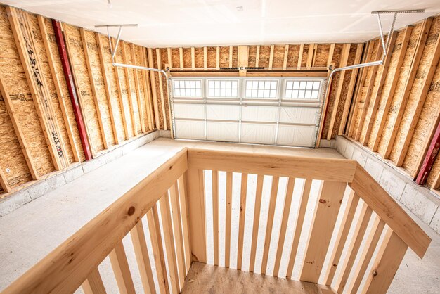 Photo interior of an unfinished garage parking with wooden stairs to a white door