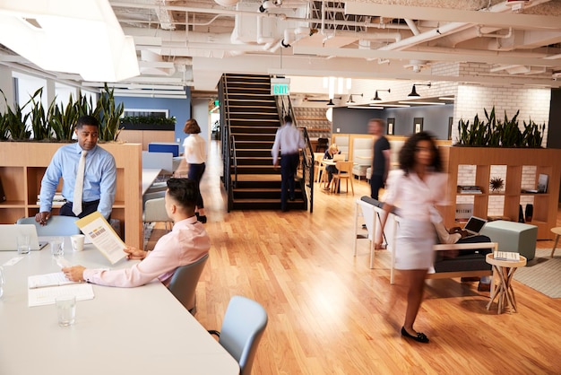 interior view of modern open plan office with blurred businessmen and businesswomen