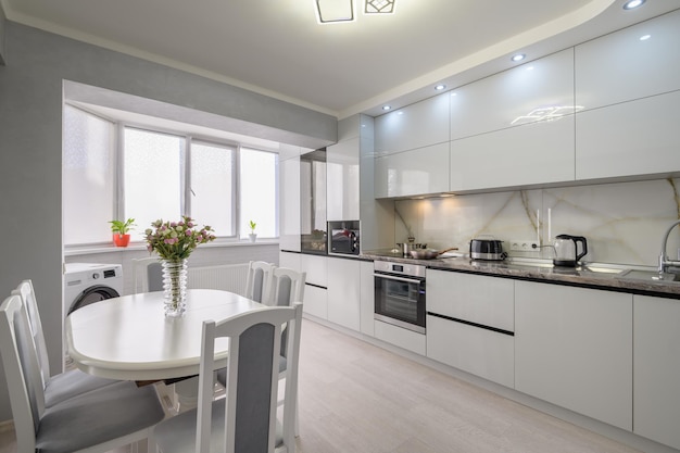 Interior of white modern kitchen with dining table