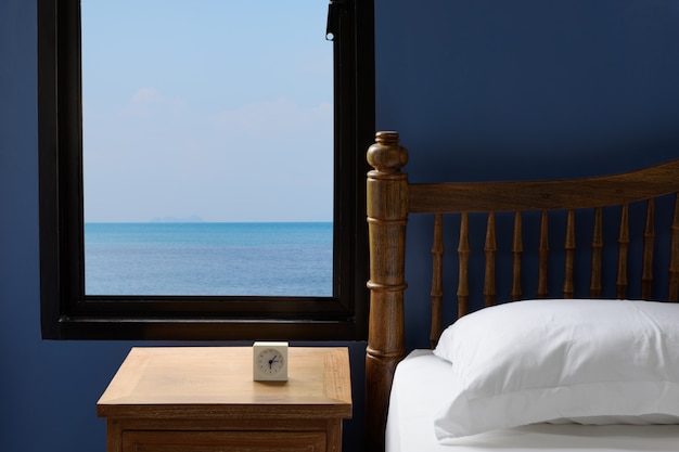 Foto cuscini e strato bianchi interni della lettiera in camera da letto blu con la vista del mare di estate nella mattina