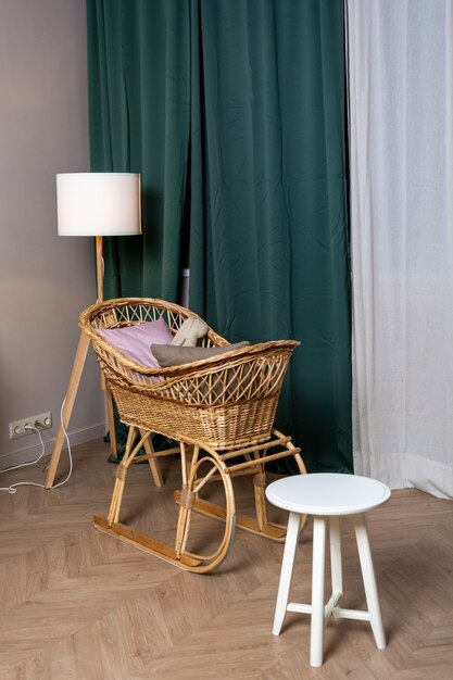 Interior, wicker cradle by the window with green curtains