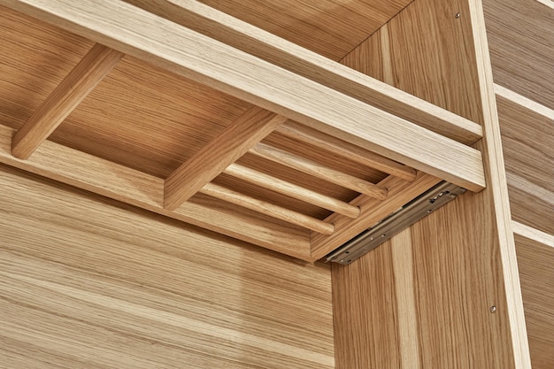 Internal details of wooden wardrobe with slide out rack for coathanger and light gray cabinet doors