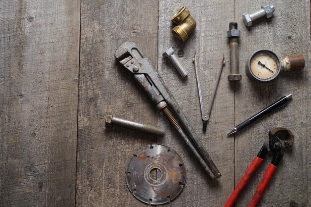 internal screws bolts manometer diamond wheel pliers pipe wrench on wooden table Top view Copy space