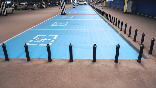 Internationaal gehandicapt symbool geschilderd in helder blauw op een winkelcentrumparkeerplaats.